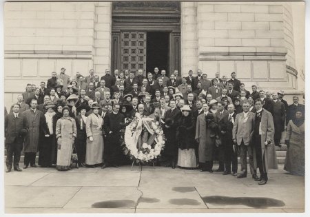 Group with wreath in front of building